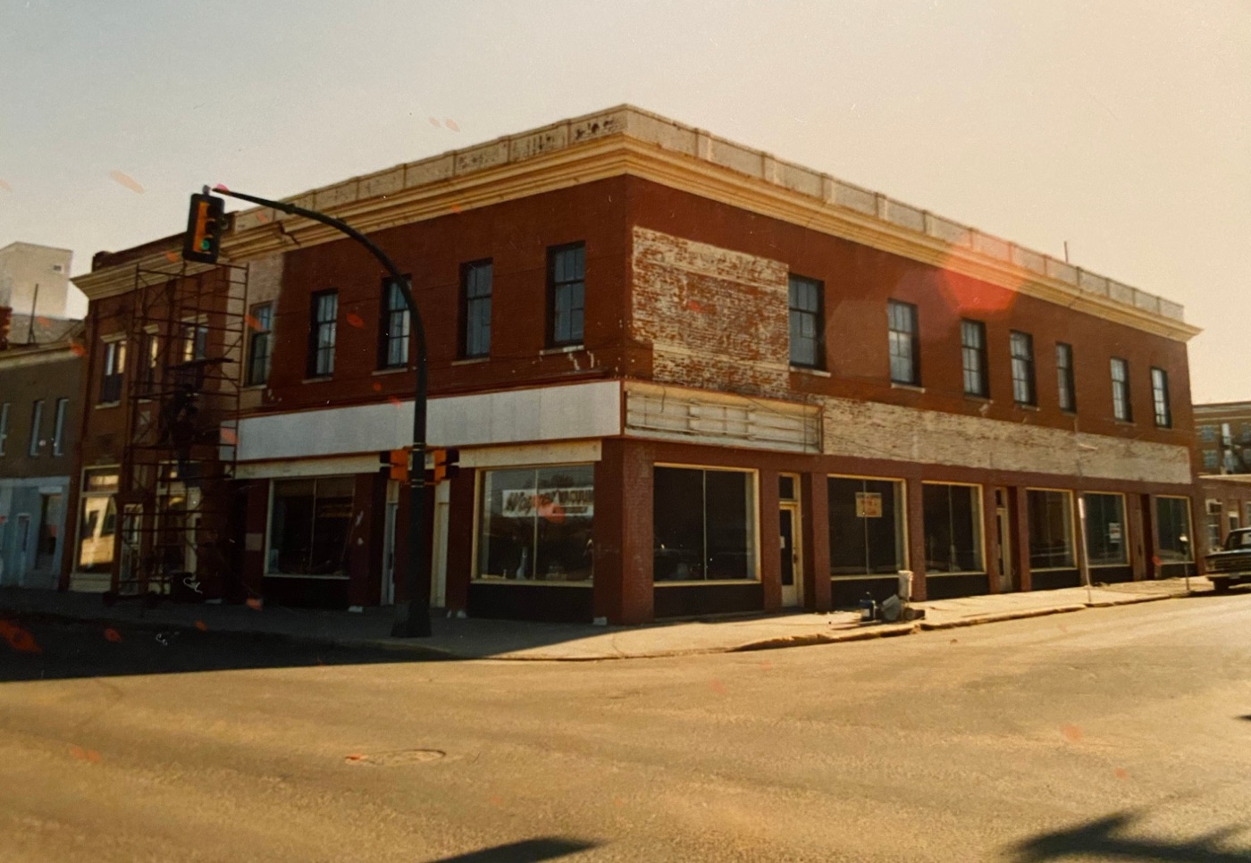 Two-storey brick corner building with peeling paint, before