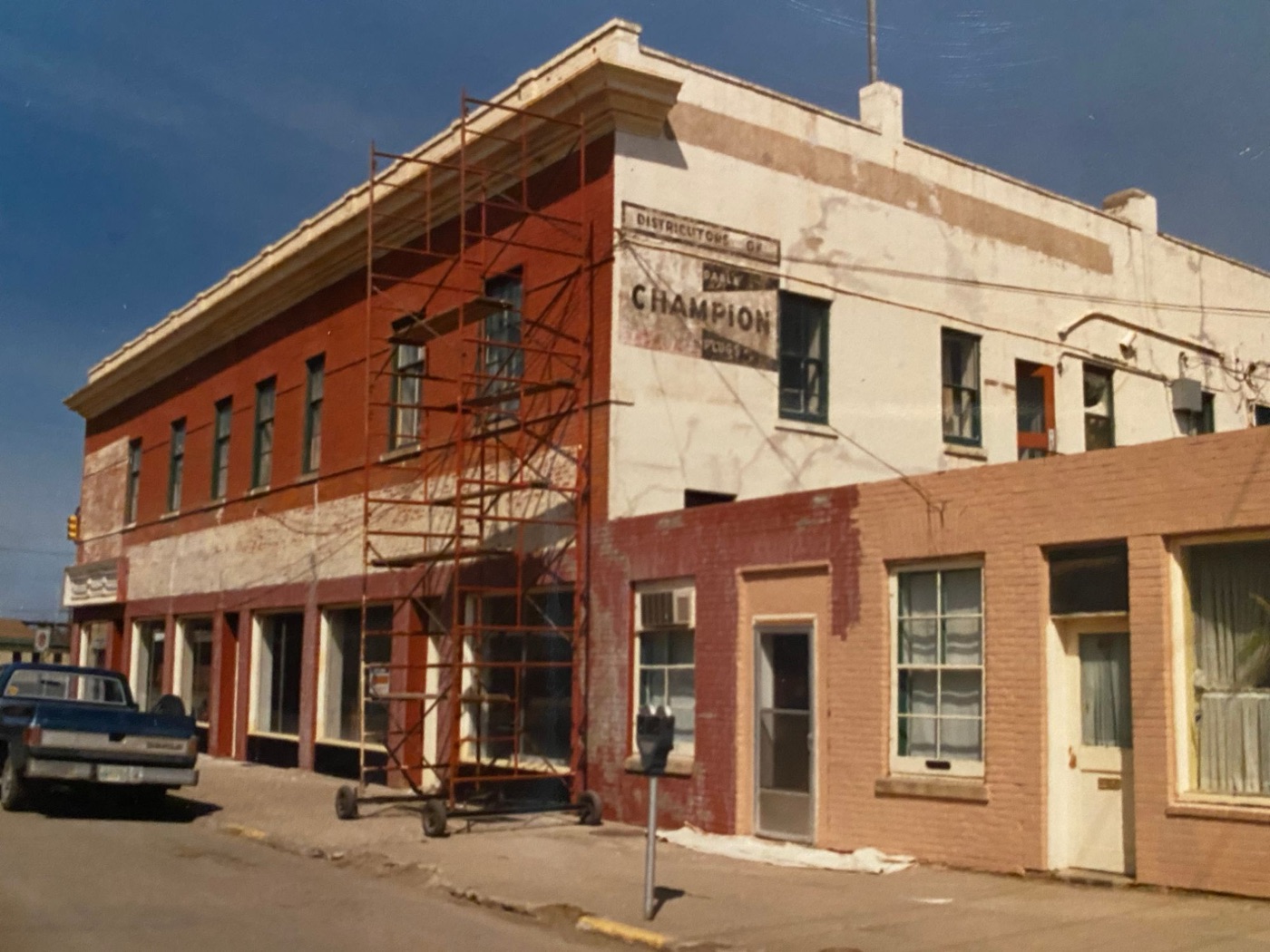 The same building half repainted, with an old hand-painted Champion sign on the side