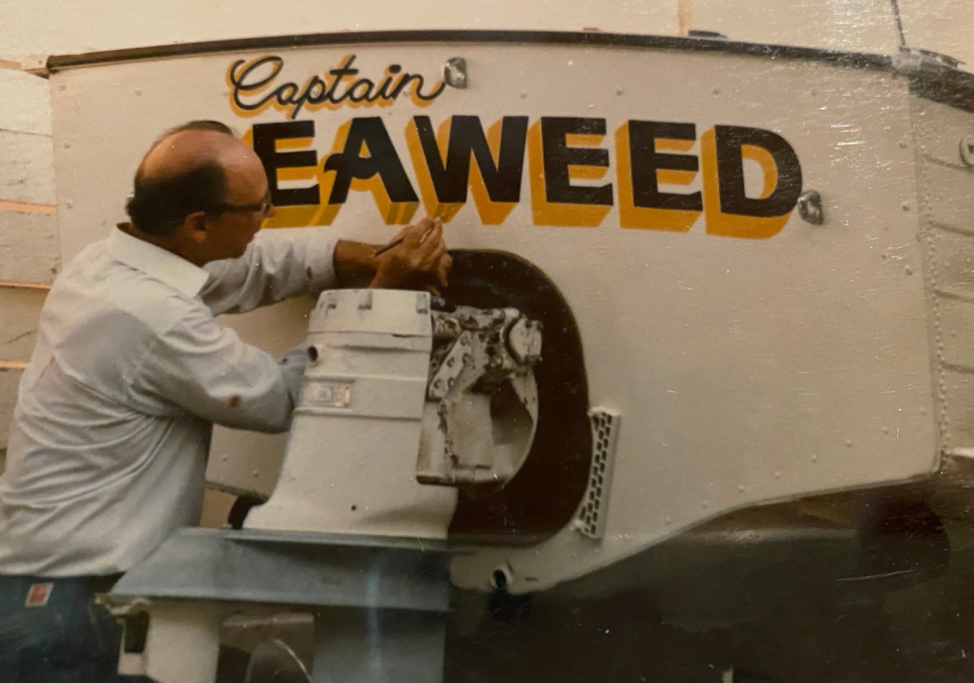 Hand-lettering the name Captain Seaweed on the stern of a boat with a fine brush