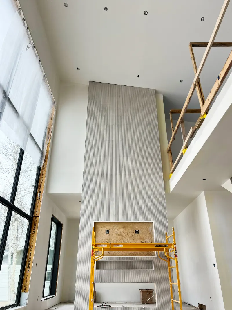 Two-storey great room with tall windows and a fireplace wall, scaffold in place
