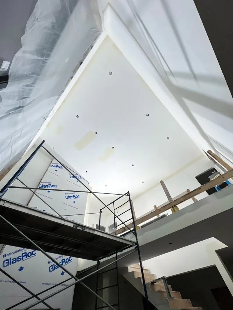 Tall vaulted ceiling with primed patches, scaffold and plastic sheeting in place