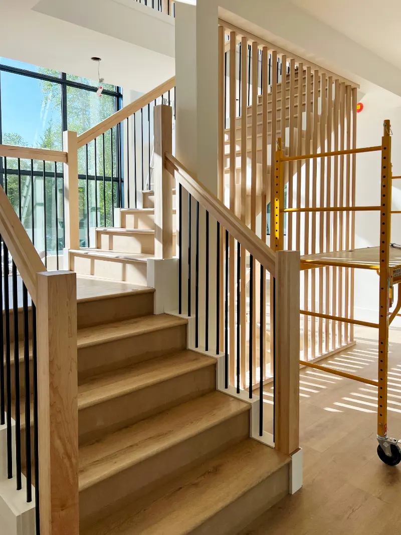 Finished staircase with wood treads, a slat wall and black balusters