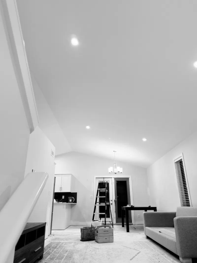 Smooth, freshly finished vaulted ceiling with pot lights over a living room