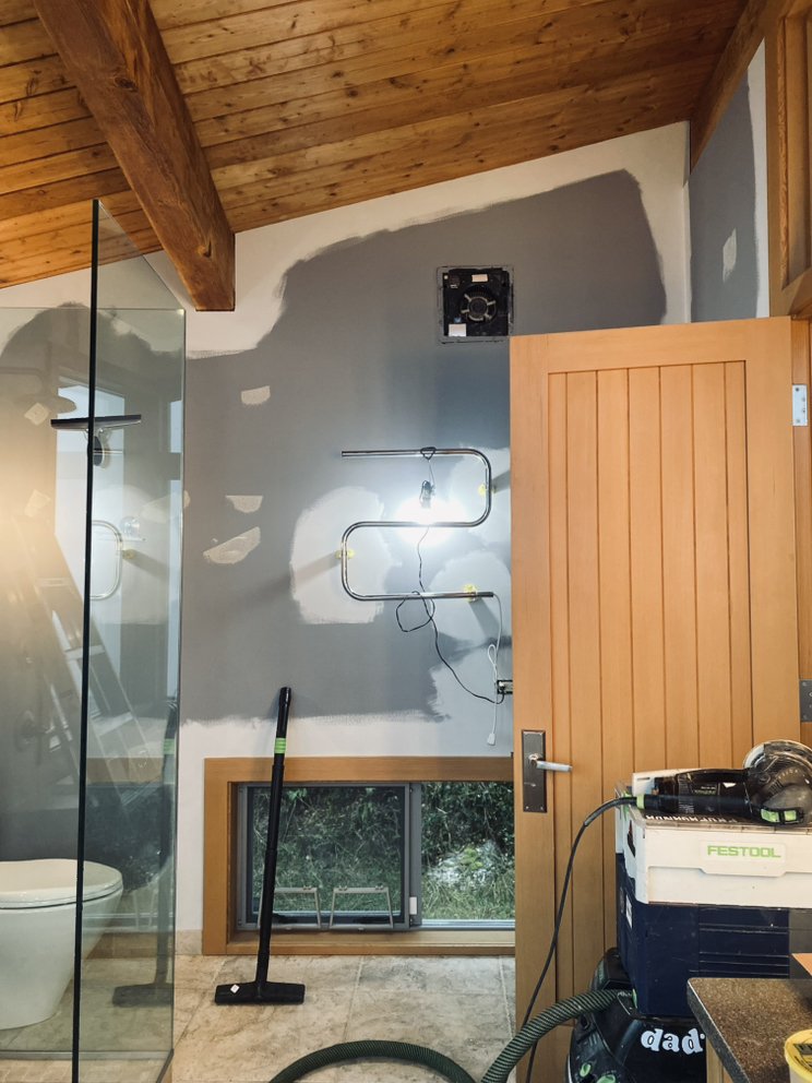Bathroom wall mid-repair with primed drywall patches